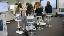 Foto. Sieben Mädchen sitzen rings um einen Tisch im Living Lab.