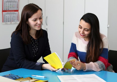 Two people looking at a booklet together