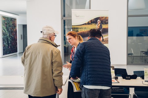 The speaker from feelSpace GmbH at their Information stand talking to a group of elderly people .