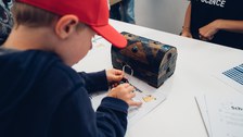 A photo of a child opening the lock of a treasure chest.