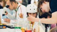 A photo of a person showing a child a test tube with colored water.
