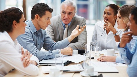 Männer und Frauen, die um einen Besprechungstisch sitzen und miteinander diskutieren