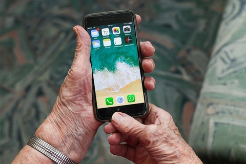 Ältere Hände halten ein Smartphone
