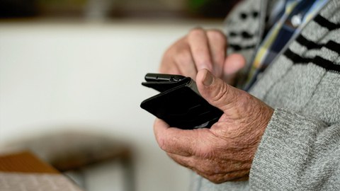 Ältere Hände halten ein Smartphone