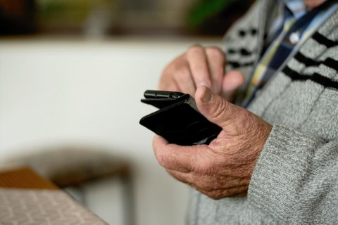 Ältere Hände halten ein Smartphone