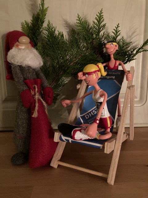 Foto Weihnachtsmannpuppe und zwei Sportlerpuppen mit Liegestuhl und Tannenzweig
