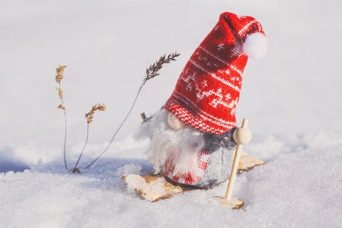 Foto: Kleiner Wichtel mit rotweißer Mütze auf Ski im Schnee