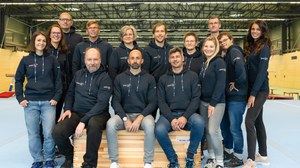 Foto: Gruppe von Menschen in einer Sporthalle, alle im dunkelblauen Kapuzenpullover mit DHSZ-Logo