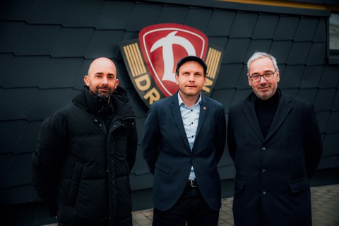 Foto: drei Männer, Marko Schimke, David Fischer und Jan Gerken stehen vor dem Logo von Dynamo Dresden