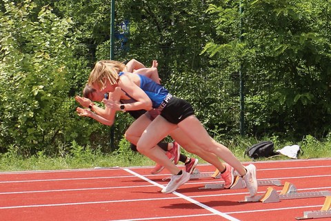 Foto von drei Sportlerinnen, die gerade zum Sprint starten