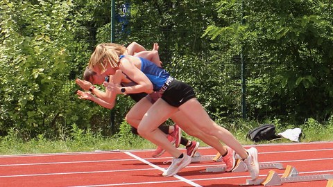 Foto von drei Sportlerinnen, die gerade zum Sprint starten