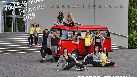 Foto: roter VW-Oldtimer-Bus vorm Haupteingang des Hörsaalzentrums mit Damenvolleyballmannschaft