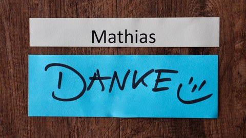 Foto: ein weißer Zettel mit Aufschrift Mathias, ein blauer Zettel mit Aufschrift Danke auf Holzfußboden