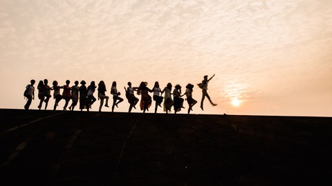 Foto: Tanzende Menschenkette vor Sonnenuntergang