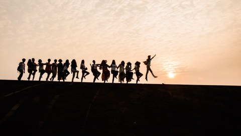 Foto: Tanzende Menschenkette vor Sonnenuntergang
