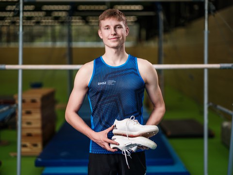 Foto junger Mann in Sportkleidung mit Stollenschuhen in der Hand