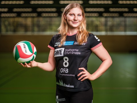 Foto: junge Frau im Sportshirt mit einem Volleyball auf der rechten Hand