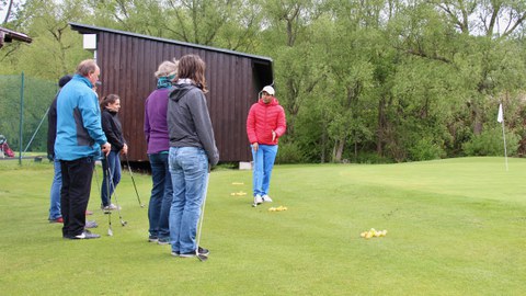 Foto: Gruppe von Personen auf grünem Rasen mit Golfschlägern