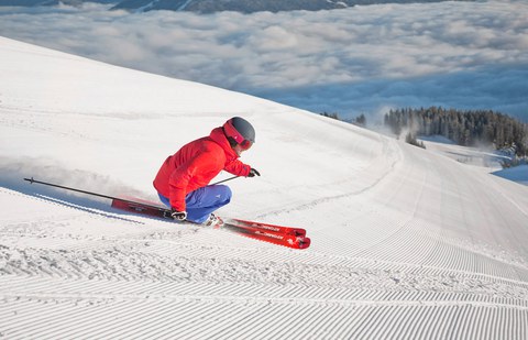 Foto Sportler mit roter Jacke fährt Abfahrtski