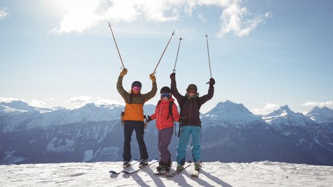 Foto drei Skifahrer stehen am Hang und schwenken ihre Stöcke hoch