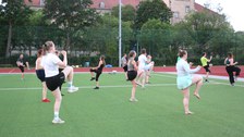 Gruppe von Menschen macht Gymnastik auf grünem Sportplatz