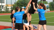 Gruppe von Menschen macht Akrobatik, im Kern der Grupe steht eine Person auf den Oberschenkeln einer 2. Person