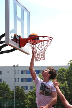 Ein Spieler ist im Sprung direkt unter dem Korb und spielt den Ball in den Korb