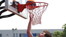 Ein Spieler ist im Sprung direkt unter dem Korb und spielt den Ball in den Korb
