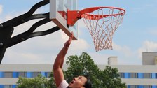 Ein Spieler ist im Sprung direkt unter dem Korb und spielt den Ball in den Korb