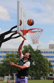 Ein Spieler ist im Sprung direkt unter dem Korb und spielt den Ball in den Korb