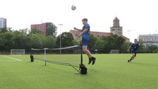 Mehrere Spieler beim Fußballtennis, der Fußball wird über ein Tennisnetz gespielt, ein Spieler beim Kopfball