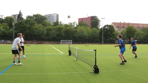Mehrere Spieler beim Fußballtennis, der Fußball wird über ein Tennisnetz gespielt