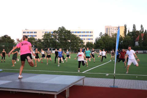 Gruppe von Menschen bei der Fitnessgymnastik auf grünem Sportplatzrasen