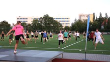 Gruppe von Menschen bei der Fitnessgymnastik auf grünem Sportplatzrasen