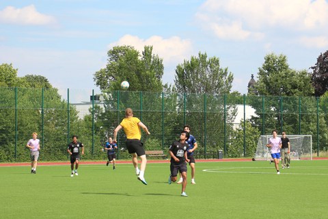 Mehrere Spieler beim Fußball, einer ist in der Luft beim Kopfball