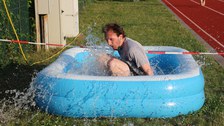 Beim Parkour-Wettbewerb: ein Mann spingt ins Mini-Wasserbecken