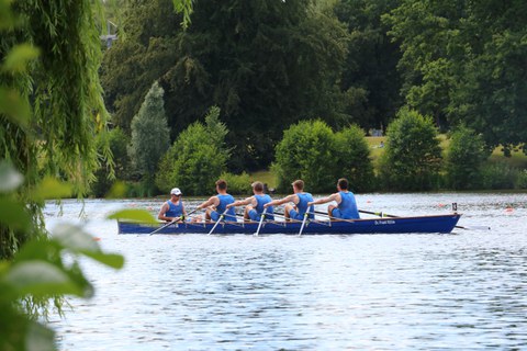 Foto vier Ruderer in ihrem Boot auf dem Wasser im blauen DHSZ-Wettkampfanzug