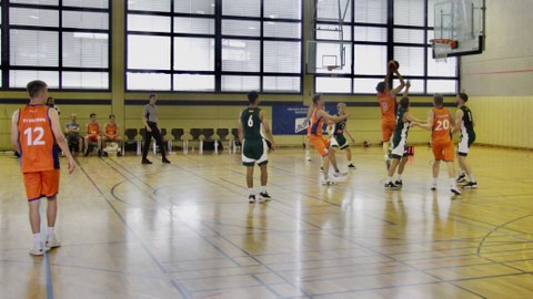 Foto: zwei Mannschaften in verschiedenfarbigen Trikots spielen Basketball gegeneinander