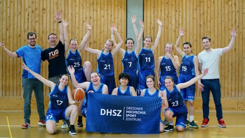 Foto Gruppe junger Frauen in Sportkleidung, jubelnd mit Banner mit DHSZ-Logo vor sich