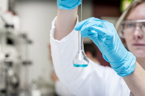 Foto einer Studentin im Labor, die mit Chemikalien arbeitet.