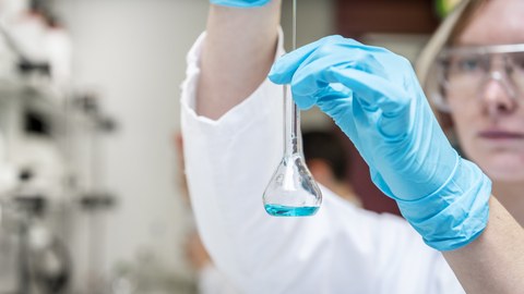 Foto einer Studentin im Labor, die mit Chemikalien arbeitet.