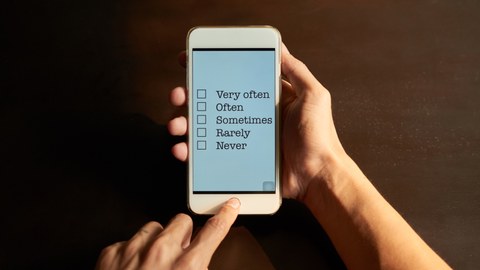 Foto eines Smartphones auf welchem ein Survey ausgefüllt werden kann, gehalten von Händen