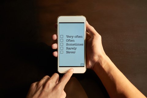 Photo of a smartphone on which a survey can be filled in, held by hands