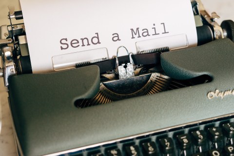 Eine Schreibmaschine, in die ein weißes Blatt Papier eingespannt ist. Auf dem Blatt steht "Send a Mail" 