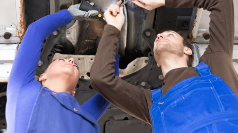 KfZ Mechatroniker reparieren Fahrzeug auf Hebebühne