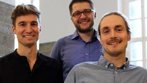 Photo: the founders of Clover Optimization, Maurice Morabel, Leopold Kuttner and Felix Tamke, stand together in a group and smile at the camera.