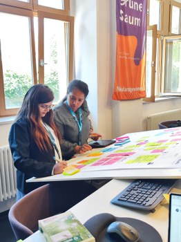 zwei Teilnehmende arbeiten zusammen an ihrem Präsentationsboard