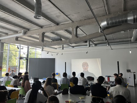 Videomessage eines externen Experten, Teilnehmende als Publikum sitzend
