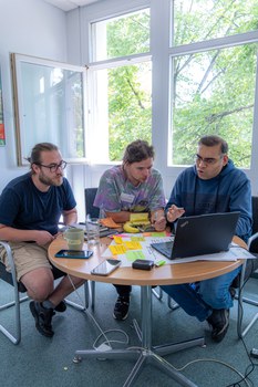 3 Teilnehmenden beraten sich über Laptop