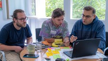 3 Teilnehmenden beraten sich über Laptop